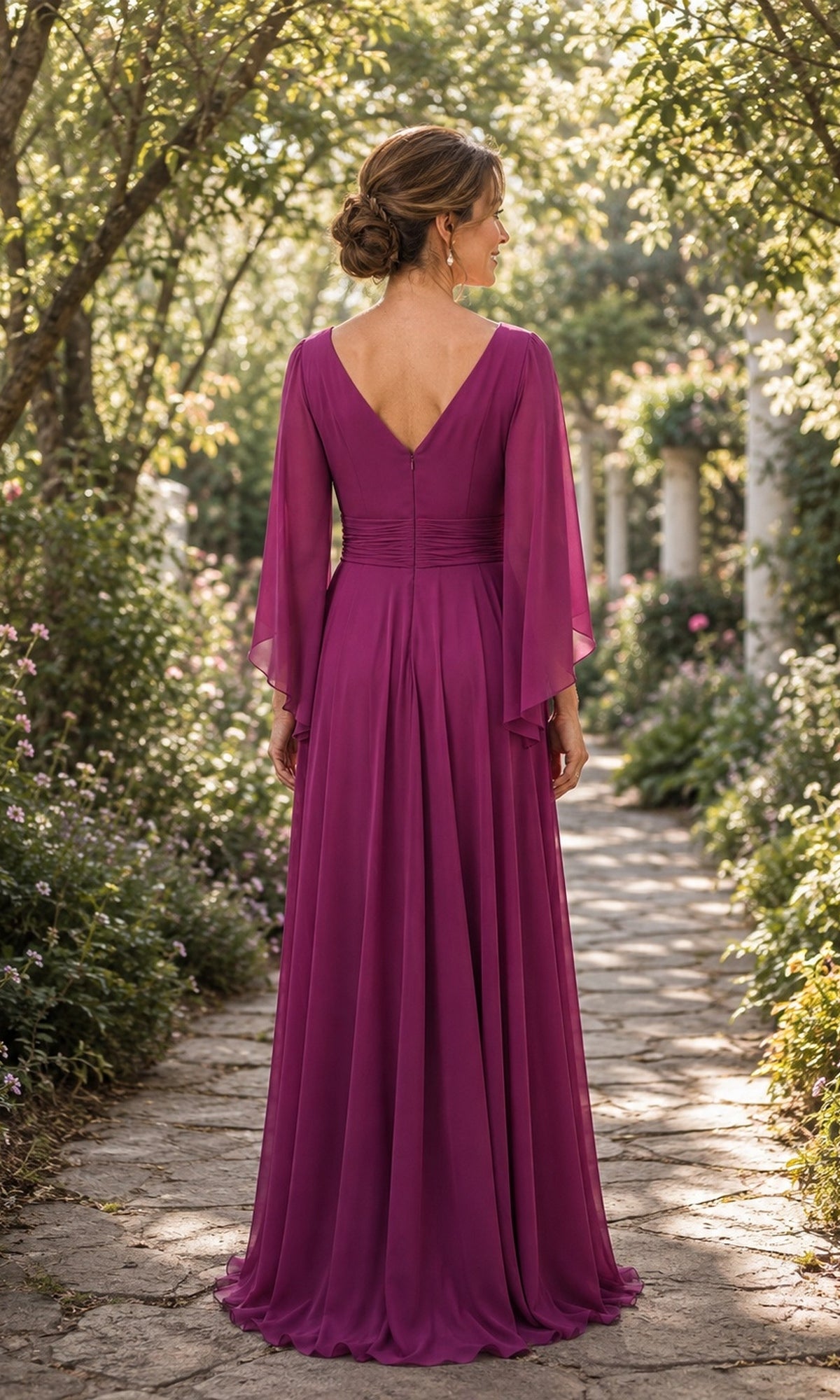 A woman stands on a stone path wearing a floor-length magenta Flutter Sleeve Chiffon Long Formal Dress: Rina Di Montella R111, featuring a V-neck back and flowing flutter sleeves.